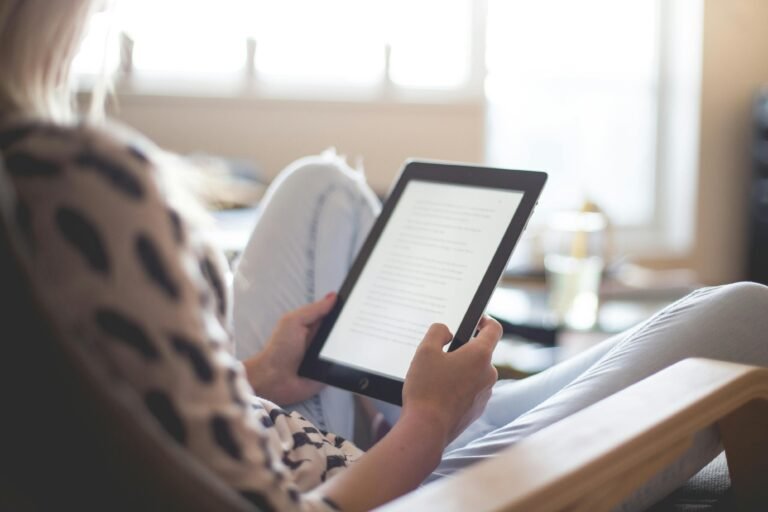 a woman relaxing in a chair while reading something on a Kindle